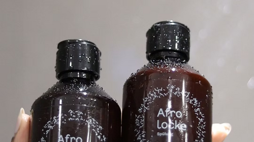 Hand hält eine Flasche Afrolocke Shampoo und eine Flasche Afrolocke Spülung
