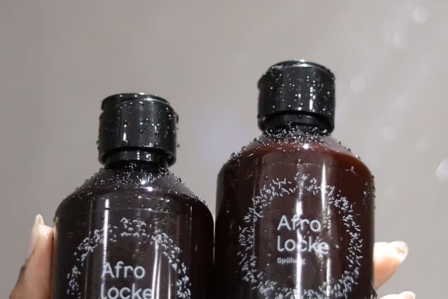 Hand hält eine Flasche Afrolocke Shampoo und eine Flasche Afrolocke Spülung