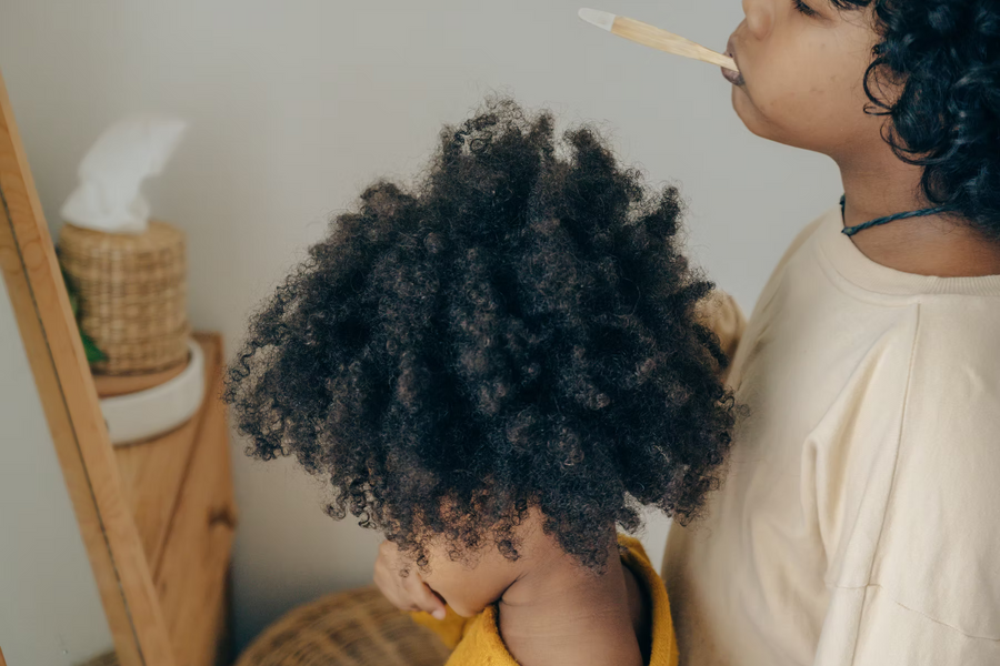 Kinder mit dichtem lockigem Haar putzen sich mit einer Bambuszahnbürste die Zähne